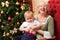 Grandmother and grandson sitting near the Christmas tree