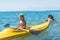 Grandmother and grandson smiling little baby boy in green baseball cap kayaking at tropical ocean sea in the day time. Positive h