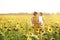 Grandmother with a hat on her shoulder and a basket of flowers holds her granddaughter in arms.