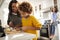 Grandmother helping her granddaughter prepare food in the kitchen, mother sitting in the background, focus on foreground