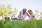 Grandmother with her grandaughter casually sitting on a blanket reading and talking in a park.