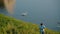 Grandmother and her grandson walk along green shore of lake, in which beautiful exquisite white swan and two cute ducks swim