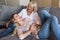 Grandmother hugging her granddaughter while sitting on a couch