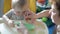 Grandmother lovingly feeds her grandson, the baby sits on a high chair.