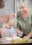 A grandmother making little pies with her granddaughter.