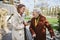 Grandmother and mature granddaughter on a walk in city park, during windy autumn day. Caregiver and senior lady with