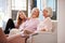 Grandmother With Mother And Adult Daughter Relaxing On Sofa