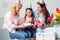 Grandmother mother and daughter together at home birthday sitting women giving cake and present to girl joyful