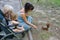 Grandmother, mother and granddaughter in a stroller feeding nuts brown squirrel, family vacation in the summer Park, top view