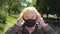 Grandmother puts on protective mask from virus COVID-19 outdoor. Portrait of old woman with medical face mask stands at