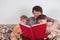 Grandmother reads a book for grandchildren. The children hugged her tenderly