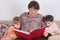 Grandmother reads an interesting book for her grandsons. The children leaned against their grandma and listen intently