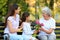 Grandmother receiving bouquet of flowers from her family on bench