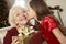 Grandmother Receiving Christmas Gift From Granddaughter At Home