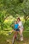 A grandmother  rides on a big red bike of a grandson  in a garden or in a forest on a sunny summer day