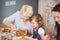 Grandmother serving granddaughter while having breakfast