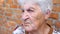 Grandmother sitting outdoor and talking with somebody. Portrait of elderly woman with serious facial expression telling