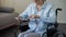 Grandmother sitting in wheelchair and scrolling family photos on tablet, gadget