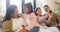 Grandmother talking to little granddaughter while her mother and father take selfies on a phone on the couch at home