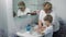 A grandmother teaches a little boy how to wash her hands with soap over a sink with running water. Personal hygiene. Protection