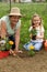 Grandmother teaching little girl gardening