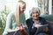 Grandmother Using Digital Tablet As Granddaughter Knits