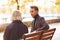 Grandmother with young guy in formal clothes have conversation in an autumn park