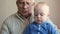 Grandpa with glasses reading a book beautiful baby. The child listens attentively to the tale. The boy about a year.