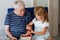Grandpa And Granddaughter Eating Raspberries At Home. Happy Preschool Girl And Senior Man Having Fun Together. Child And