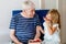 Grandpa And Granddaughter Eating Raspberries At Home. Happy Preschool Girl And Senior Man Having Fun Together. Child And