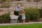 Grandpa helping little girl with hat on walk with toy buggy