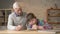 Grandpa helps a grandson with homework. Elderly man helps a young fat child to do homework. Home comfort, family idyll