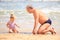 Grandpa Little Girl Sit on Wet Sand Look at Shell by Surf