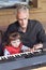 Grandpa teaches little girl to play piano. Concept of music study and creative hobby