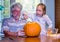 Grandpa watches as girl scoops out a pumpkin