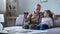 Grandpa watching photo album with grandson, recalling stories from happy youth