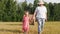 Grandparent walks with granddaughter in the meadow