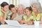 Grandparents with adult daughter and grandchildren using laptop