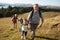 Grandparents With Grandchildren Climbing Hill On Hike Through Countryside In Lake District UK Together