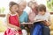 Grandparents And Grandchildren Reading Book On Garden Seat