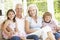 Grandparents And Grandchildren Sitting On Cane Sofa At Home