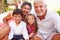 Grandparents With Grandchildren Sitting On Seat In Gardenï¿½