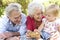 Grandparents And Granddaughter Enjoying Picnic Together