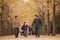 Grandparents and granddaughter holding hands and walking in the park in the fall