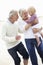 Grandparents And Granddaughter Walking Along Beach Together