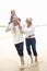 Grandparents And Granddaughter Walking Along Beach Together