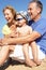 Grandparents And Grandson Sitting On Beach