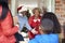 Grandparents Greeting Mother And Children As They Arrive For Visit On Christmas Day With Gifts