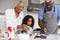 Grandparents In Kitchen With Granddaughter Making Pancakes Together