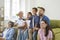 Grandparents, mother, father and two little kids are watching television programs together.